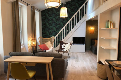 Aménagement d'une salle de séjour éclectique ouverte avec un mur blanc, parquet clair, un téléviseur encastré, poutres apparentes et du papier peint.