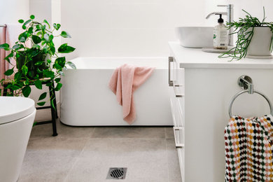 Inspiration for a small contemporary ensuite bathroom in Sydney with shaker cabinets, white cabinets, a corner bath, a corner shower, a one-piece toilet, white tiles, porcelain tiles, white walls, porcelain flooring, a vessel sink, engineered stone worktops, grey floors, a hinged door, white worktops, a single sink and a floating vanity unit.