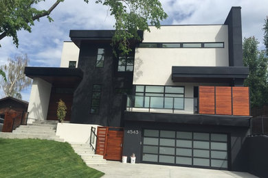 Large modern white three-story stucco flat roof idea in Calgary
