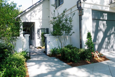 Example of a mid-sized classic white two-story stucco exterior home design in New Orleans with a clipped gable roof