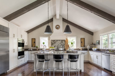 Large trendy u-shaped dark wood floor and brown floor enclosed kitchen photo in San Francisco with an undermount sink, shaker cabinets, white cabinets, granite countertops, gray backsplash, stone slab backsplash, stainless steel appliances and an island