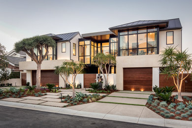 Inspiration for a large contemporary two-storey stucco beige house exterior in Orange County with a gable roof and a metal roof.
