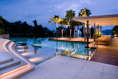 Design ideas for an expansive modern backyard custom-shaped infinity pool in Tampa with a hot tub and concrete pavers.