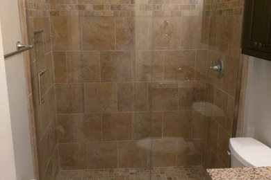 Example of a mid-sized trendy beige tile and cement tile ceramic tile and beige floor bathroom design in Other with raised-panel cabinets, brown cabinets, a two-piece toilet, gray walls, an undermount sink and granite countertops