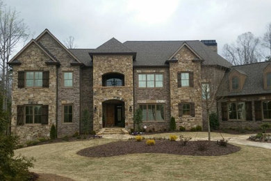 Large traditional brown two-story stone exterior home idea in Atlanta with a hip roof