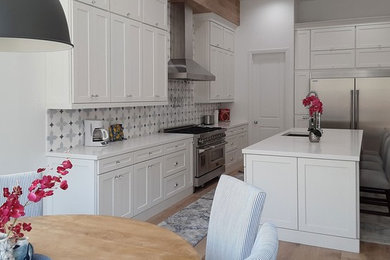 Example of a mid-sized trendy l-shaped medium tone wood floor and gray floor eat-in kitchen design in San Diego with an undermount sink, shaker cabinets, white cabinets, quartz countertops, multicolored backsplash, mosaic tile backsplash, stainless steel appliances, an island and white countertops