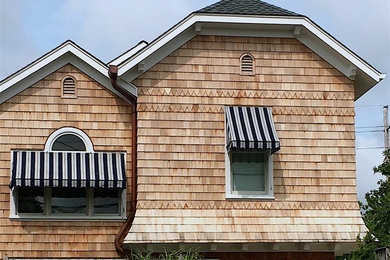 Foto della villa piccola multicolore stile marinaro a due piani con rivestimento in legno, falda a timpano e copertura a scandole