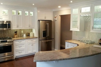 Eat-in kitchen - mid-sized transitional u-shaped medium tone wood floor and brown floor eat-in kitchen idea in Other with shaker cabinets, white cabinets, granite countertops, brown backsplash, stone slab backsplash, white appliances, a peninsula and a farmhouse sink