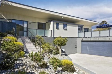 Inspiration for an expansive beach style two-storey white exterior in Dunedin with mixed siding and a flat roof.