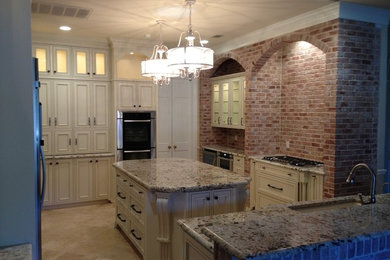 Large elegant travertine floor eat-in kitchen photo in Austin with an undermount sink, glass-front cabinets, distressed cabinets, granite countertops, stainless steel appliances and an island