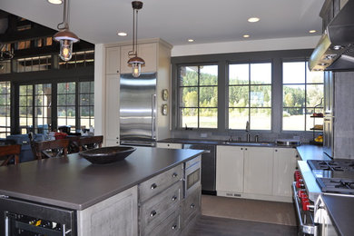This is an example of a large country l-shaped eat-in kitchen in Seattle with an undermount sink, shaker cabinets, distressed cabinets, quartz benchtops, grey splashback, stone tile splashback, stainless steel appliances, medium hardwood floors and with island.
