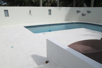 This is an example of a tropical backyard pool in Miami with tile.