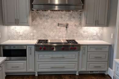 Inspiration for a large medium tone wood floor kitchen remodel in Atlanta with gray cabinets, gray backsplash, stainless steel appliances and white countertops