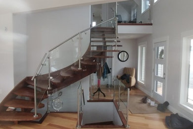 Diseño de escalera suspendida contemporánea grande sin contrahuella con escalones de madera y barandilla de vidrio