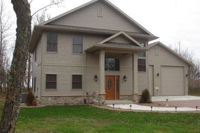 Example of a large classic beige two-story vinyl exterior home design in Other with a clipped gable roof