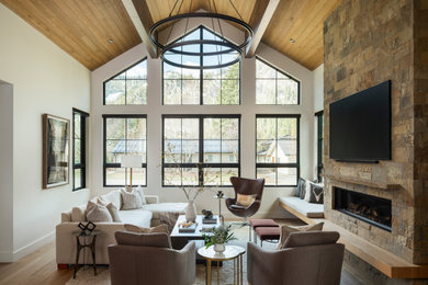 Mid-sized transitional open concept medium tone wood floor, brown floor and vaulted ceiling living room photo in Other with white walls, a stacked stone fireplace and a wall-mounted tv