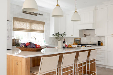 Example of a large transitional light wood floor and beige floor kitchen design in Charleston with an undermount sink, shaker cabinets, white cabinets, quartz countertops, white backsplash, ceramic backsplash, an island and white countertops