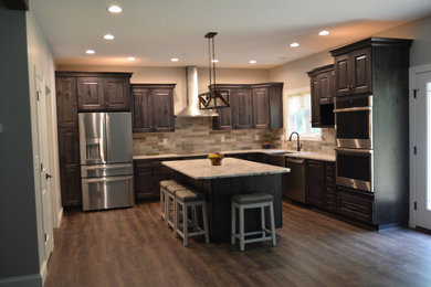 Inspiration for a large transitional l-shaped vinyl floor and brown floor kitchen pantry remodel in Other with a farmhouse sink, raised-panel cabinets, dark wood cabinets, quartz countertops, beige backsplash, subway tile backsplash, stainless steel appliances, an island and beige countertops
