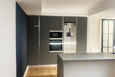 Imagen de cocina moderna pequeña con fregadero encastrado, encimera de cuarzo compacto, salpicadero negro, suelo de madera clara, una isla y encimeras grises