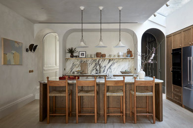 Inspiration for a medium sized traditional l-shaped open plan kitchen in London with shaker cabinets, medium wood cabinets, marble worktops, multi-coloured splashback, marble splashback, black appliances, light hardwood flooring, an island, multicoloured worktops and beige floors.