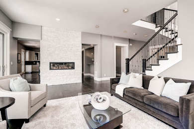 Example of a large trendy enclosed dark wood floor living room design in Denver with gray walls, a ribbon fireplace, a stone fireplace and a wall-mounted tv