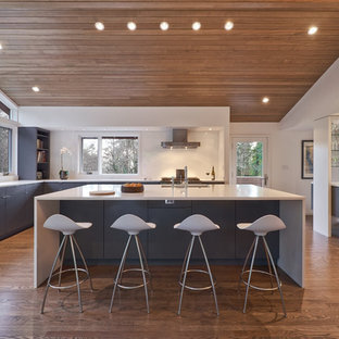 Expansive modern u-shaped kitchen pantry in Portland with an undermount sink, flat-panel cabinets, grey cabinets, quartzite benchtops, white splashback, glass sheet splashback, stainless steel appliances, medium hardwood floors, with island and brown floor.