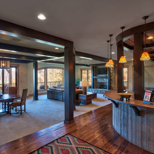 他の地域のラスティックスタイルのおしゃれな地下室 (半地下 (ドアあり)、ベージュの壁、濃色無垢フローリング、標準型暖炉、石材の暖炉まわり、茶色い床) の写真