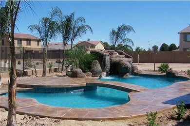 Inspiration for a large traditional backyard custom-shaped lap pool in Phoenix with a water feature and natural stone pavers.