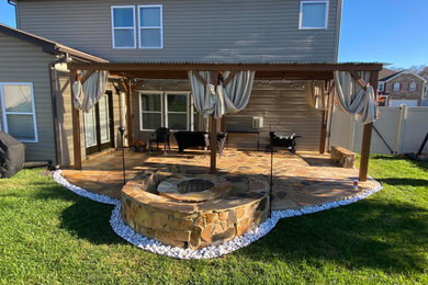Patio - large contemporary backyard stone patio idea in Other with a fire pit, a fireplace and an awning