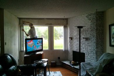 Kleines, Repräsentatives, Offenes Klassisches Wohnzimmer mit beiger Wandfarbe, braunem Holzboden, Eckkamin, Kaminumrandung aus Backstein und freistehendem TV in Calgary