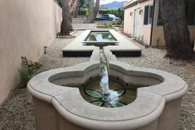 Modelo de piscina con fuente natural mediterránea de tamaño medio a medida en patio lateral con gravilla