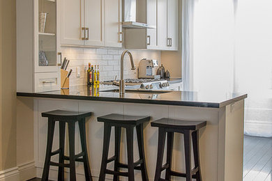 Eat-in kitchen - mid-sized modern u-shaped dark wood floor eat-in kitchen idea in Toronto with an undermount sink, shaker cabinets, white cabinets, granite countertops, white backsplash, ceramic backsplash and stainless steel appliances