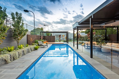 This is an example of a large contemporary backyard rectangular pool in Melbourne with with a pool and natural stone pavers.