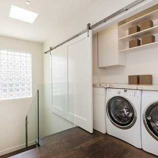 This is an example of a small traditional single-wall laundry cupboard in San Francisco with white cabinets, granite worktops, a side by side washer and dryer, flat-panel cabinets, beige walls, dark hardwood flooring and brown floors.