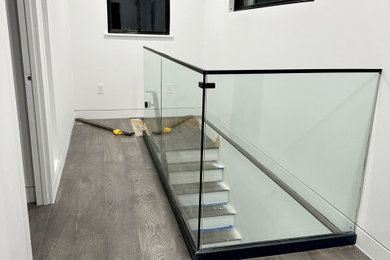 Large minimalist wooden straight glass railing staircase photo in San Francisco with painted risers