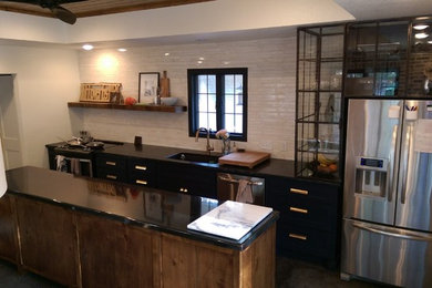 Open concept kitchen - mid-sized transitional galley concrete floor open concept kitchen idea in Dallas with an undermount sink, shaker cabinets, black cabinets, soapstone countertops, white backsplash, matchstick tile backsplash, stainless steel appliances and an island