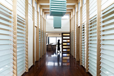 Large beach style hallway in Melbourne with white walls and medium hardwood floors.