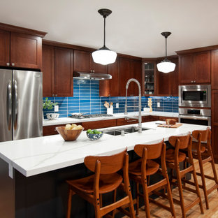 Eat-in kitchen - large transitional l-shaped light wood floor and yellow floor eat-in kitchen idea in San Francisco with a double-bowl sink, shaker cabinets, brown cabinets, blue backsplash, glass tile backsplash, stainless steel appliances, an island and white countertops