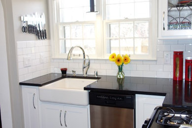 Enclosed kitchen - small transitional l-shaped dark wood floor and brown floor enclosed kitchen idea in Milwaukee with a farmhouse sink, shaker cabinets, white cabinets, quartz countertops, white backsplash, ceramic backsplash and stainless steel appliances