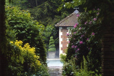 This is an example of an expansive classic back partial sun garden for summer in London with natural stone paving.