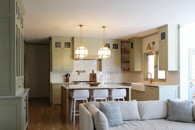 Inspiration for a mid-sized transitional u-shaped light wood floor eat-in kitchen remodel in Kansas City with a farmhouse sink, shaker cabinets, green cabinets, quartz countertops, white backsplash, subway tile backsplash, white appliances, an island and white countertops