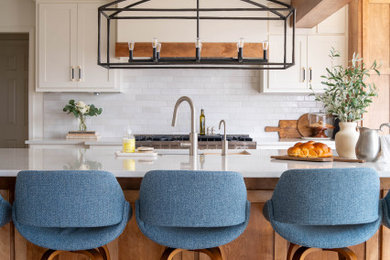 Eat-in kitchen - large french country single-wall light wood floor, white floor and exposed beam eat-in kitchen idea in Kansas City with an island, an undermount sink, shaker cabinets, white cabinets, quartz countertops, beige backsplash, ceramic backsplash, stainless steel appliances and white countertops
