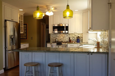 Mid-sized transitional u-shaped medium tone wood floor and brown floor eat-in kitchen photo in St Louis with an undermount sink, raised-panel cabinets, white cabinets, granite countertops, green backsplash, glass sheet backsplash, stainless steel appliances and a peninsula