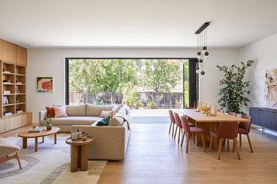 Large danish open concept light wood floor and brown floor living room photo in San Francisco with white walls, no fireplace and a wall-mounted tv