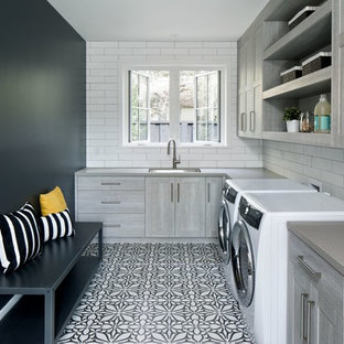 Design ideas for a farmhouse l-shaped utility room in San Francisco with a submerged sink, flat-panel cabinets, grey cabinets, black walls and a side by side washer and dryer.