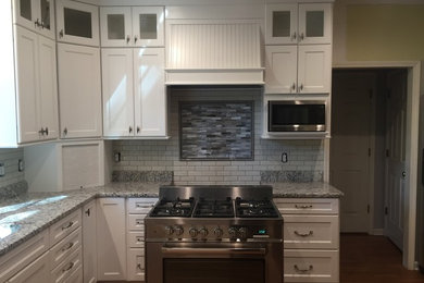 Mid-sized transitional u-shaped dark wood floor kitchen photo in Atlanta with shaker cabinets, white cabinets, granite countertops, white backsplash, subway tile backsplash and stainless steel appliances
