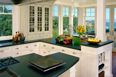 Large transitional u-shaped medium tone wood floor eat-in kitchen photo in San Francisco with an undermount sink, shaker cabinets, white cabinets, granite countertops, black backsplash, stone slab backsplash, paneled appliances and two islands