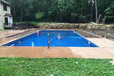 Diseño de piscina alargada clásica de tamaño medio rectangular en patio trasero con adoquines de hormigón