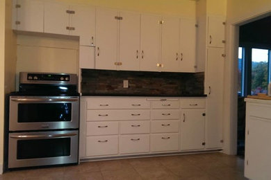 Example of a small transitional l-shaped ceramic tile eat-in kitchen design in Seattle with a drop-in sink, flat-panel cabinets, white cabinets, granite countertops, multicolored backsplash, stone tile backsplash and stainless steel appliances