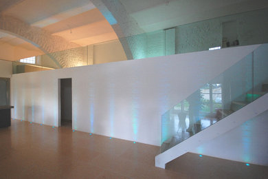 Modelo de salón abierto moderno grande con paredes blancas, suelo de mármol, chimeneas suspendidas y televisor colgado en la pared